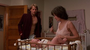 Movie still from “Terms of Endearment” (1983), directed by James L. Brooks – A man and a woman standing next to a baby in a crib; Medium shot, Low angle