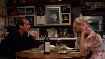 Movie still from “Terms of Endearment” (1983), directed by James L. Brooks – A man and a woman sitting at a table with a bottle of wine; Medium shot, Over the shoulder angle