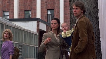 Movie still from “Terms of Endearment” (1983), directed by James L. Brooks – A man and a woman holding a baby in front of a brick building; Medium shot, Low angle