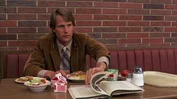 Movie still from “Terms of Endearment” (1983), directed by James L. Brooks – A man sitting at a table with a plate of food; Medium shot, High angle