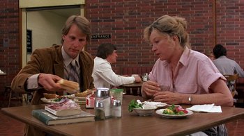 Movie still from “Terms of Endearment” (1983), directed by James L. Brooks – A man and a woman sitting at a table with a sandwich; Medium shot, Over the shoulder angle