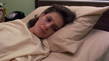 Movie still from “Terms of Endearment” (1983), directed by James L. Brooks – A woman laying in a bed under a blanket; Close Up shot, High angle