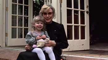 Movie still from “Terms of Endearment” (1983), directed by James L. Brooks – An older woman and a young girl sitting on a suitcase; Medium shot, High angle