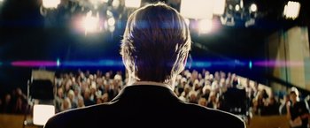 Movie still from “Thank You for Smoking” (2005), directed by Jason Reitman – A man in a crowd of people is seen from the back; Medium shot, Over the shoulder angle