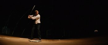 Movie still from “Thank You for Smoking” (2005), directed by Jason Reitman – A man in a white shirt and black pants holding a baseball bat; Wide shot, Low angle