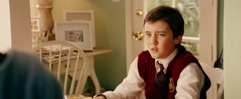 Movie still from “Thank You for Smoking” (2005), directed by Jason Reitman – A young boy sitting at a dining room table in front of a white chair; Close Up shot, Over the shoulder angle