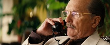 Movie still from “Thank You for Smoking” (2005), directed by Jason Reitman – An older man talking on a phone while wearing glasses; Close Up shot, Over the shoulder angle