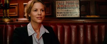 Movie still from “Thank You for Smoking” (2005), directed by Jason Reitman – A woman sitting in front of a sign in front of a booth; Close Up shot, Over the shoulder angle