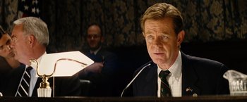 Movie still from “Thank You for Smoking” (2005), directed by Jason Reitman – A man wearing a suit and tie sitting at a table; Close Up shot, Over the shoulder angle