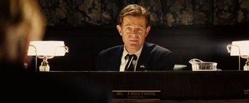 Movie still from “Thank You for Smoking” (2005), directed by Jason Reitman – A man in a suit and tie sitting in front of a desk; Medium shot, Low angle