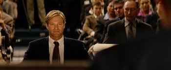 Movie still from “Thank You for Smoking” (2005), directed by Jason Reitman – A man in a suit and tie sitting next to other people; Close Up shot, Over the shoulder angle