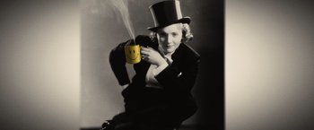 Movie still from “Thank You for Smoking” (2005), directed by Jason Reitman – A woman in a top hat holding a cup of coffee; Medium shot, Low angle