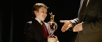 Movie still from “Thank You for Smoking” (2005), directed by Jason Reitman – A man is handing a trophy to a person; Medium shot, Low angle