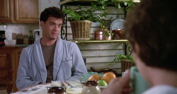 Movie still from “The 'Burbs” (1989), directed by Joe Dante – A man sitting at a table with a bowl of fruit in front of him; Medium shot, Over the shoulder angle