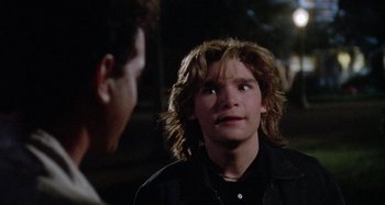 Movie still from “The 'Burbs” (1989), directed by Joe Dante – A young man with long brown hair is looking at another young man; Close Up shot, Over the shoulder angle