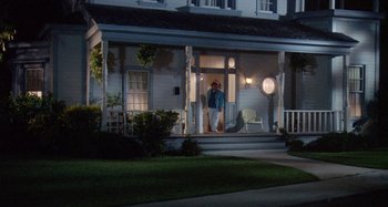 Movie still from “The 'Burbs” (1989), directed by Joe Dante – A man standing on the porch of a house at night; Wide shot, High angle