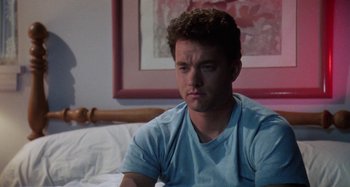 Movie still from “The 'Burbs” (1989), directed by Joe Dante – A man sitting on top of a bed in front of a painting; Close Up shot, Low angle