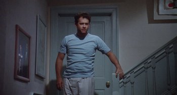 Movie still from “The 'Burbs” (1989), directed by Joe Dante – A man standing in front of a door holding a remote control; Medium shot, Low angle