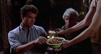 Movie still from “The 'Burbs” (1989), directed by Joe Dante – A man holding a bowl of food while two other people look on; Medium shot, Low angle