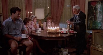 Movie still from “The 'Burbs” (1989), directed by Joe Dante – A group of people sitting around a table with lit candles; Wide shot, High angle