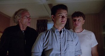 Movie still from “The 'Burbs” (1989), directed by Joe Dante – A group of men standing next to each other in a room; Medium shot, Low angle