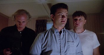 Movie still from “The 'Burbs” (1989), directed by Joe Dante – A group of men standing next to each other in a room; Medium shot, Low angle