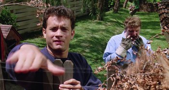 Movie still from “The 'Burbs” (1989), directed by Joe Dante – Two men in a yard with a fence; Medium shot, Over the shoulder angle