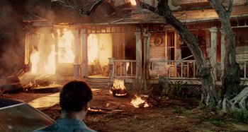 Movie still from “The 'Burbs” (1989), directed by Joe Dante – A man standing in front of a fire in a house; Wide shot, Over the shoulder angle