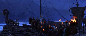 Movie still from “The 13th Warrior” (1999), directed by Michael Crichton – A group of people standing around a boat at night with torches; Extreme Wide shot, High angle