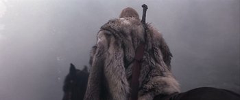 Movie still from “The 13th Warrior” (1999), directed by Michael Crichton – A person in a fur coat and a sword; Medium shot, Low angle