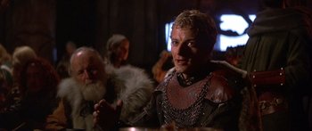 Movie still from “The 13th Warrior” (1999), directed by Michael Crichton – A man in a leather jacket sitting at a table; Close Up shot, Over the shoulder angle