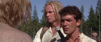 Movie still from “The 13th Warrior” (1999), directed by Michael Crichton – A man with long blonde hair is holding a microphone in his hand; Close Up shot, Low angle