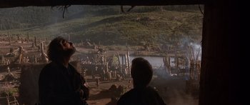 Movie still from “The 13th Warrior” (1999), directed by Michael Crichton – A group of people standing on top of a dirt field; Extreme Wide shot, Over the shoulder angle