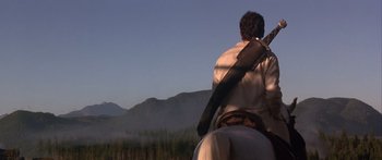 Movie still from “The 13th Warrior” (1999), directed by Michael Crichton – A man riding a horse with a rifle strapped to his back; Wide shot, Low angle