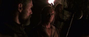 Movie still from “The 13th Warrior” (1999), directed by Michael Crichton – A man with long blonde hair is looking at the camera; Close Up shot, Over the shoulder angle