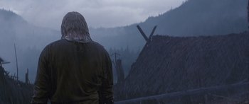 Movie still from “The 13th Warrior” (1999), directed by Michael Crichton – A man standing in front of a hut in the mountains; Medium shot, Low angle