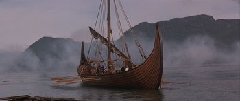 Movie still from “The 13th Warrior” (1999), directed by Michael Crichton – A group of people in a boat on a body of water; Extreme Wide shot, High angle