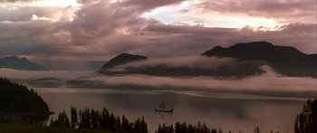 Movie still from “The 13th Warrior” (1999), directed by Michael Crichton – A boat floating on top of a body of water near trees; Extreme Wide shot, Low angle