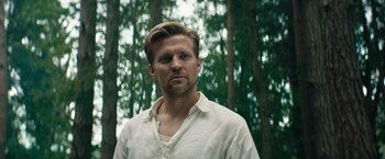 Movie still from “Out Stealing Horses” (2019), directed by Hans Petter Moland – A person wearing a white shirt near a forest; Close Up shot, Low angle