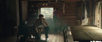Movie still from “Out Stealing Horses” (2019), directed by Hans Petter Moland – A woman sitting on a chair in a room; Wide shot, Low angle