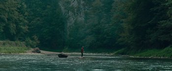 Movie still from “Out Stealing Horses” (2019), directed by Hans Petter Moland – A man standing on a surfboard in the water; Extreme Wide shot, High angle
