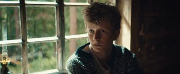 Movie still from “Out Stealing Horses” (2019), directed by Hans Petter Moland – A young man in a sweater looking out of a window; Close Up shot, Over the shoulder angle