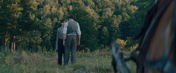 Movie still from “Out Stealing Horses” (2019), directed by Hans Petter Moland – A man and a woman standing in a field near a forest; Wide shot, Over the shoulder angle