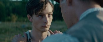 Movie still from “Out Stealing Horses” (2019), directed by Hans Petter Moland – A young man looking at a older man in a field; Close Up shot, Over the shoulder angle