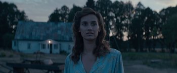 Movie still from “Out Stealing Horses” (2019), directed by Hans Petter Moland – A woman with long brown hair wearing a blue shirt; Close Up shot, Over the shoulder angle