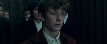 Movie still from “Out Stealing Horses” (2019), directed by Hans Petter Moland – A young man in a brown jacket looking to his left; Close Up shot, Low angle