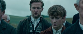 Movie still from “Out Stealing Horses” (2019), directed by Hans Petter Moland – Two men standing next to each other on a field; Close Up shot, Over the shoulder angle