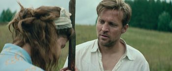 Movie still from “Out Stealing Horses” (2019), directed by Hans Petter Moland – A man and a woman are standing in a field; Close Up shot, Over the shoulder angle