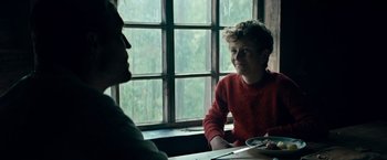 Movie still from “Out Stealing Horses” (2019), directed by Hans Petter Moland – A man sitting at a table in front of another man; Medium shot, Over the shoulder angle