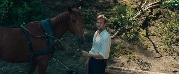Movie still from “Out Stealing Horses” (2019), directed by Hans Petter Moland – A man standing next to a horse in a field; Medium shot, Low angle